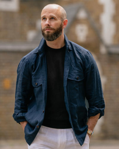 Navy overshirt over brown T-shirt, white trousers